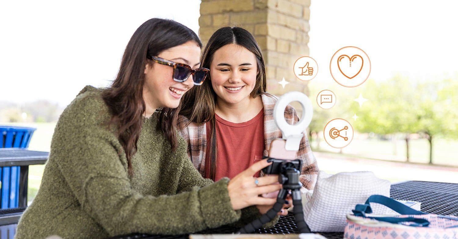 Student creating a TikTok video on a university campus with engagement icons floating on screen
